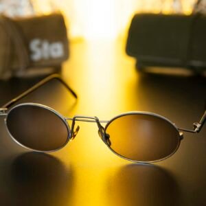 Close-up of sleek sunglasses on a shiny black surface with warm golden light.
