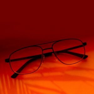 Stylish eyeglasses with black frames on a vibrant orange surface, creating a bold visual contrast.