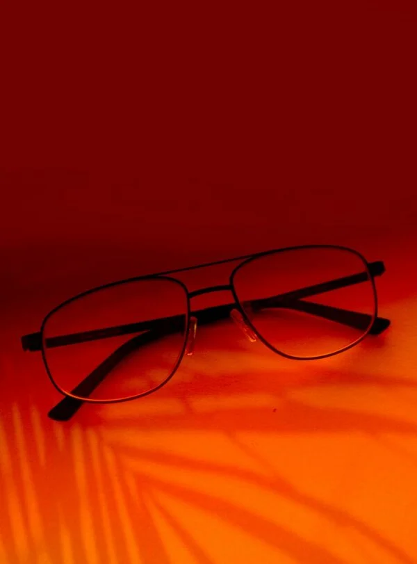 Stylish eyeglasses with black frames on a vibrant orange surface, creating a bold visual contrast.